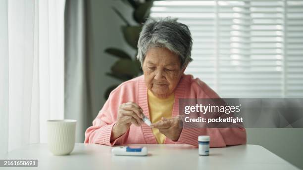 elderly patient with diabetes using blood glucose meter. - glucose stockfoto's en -beelden