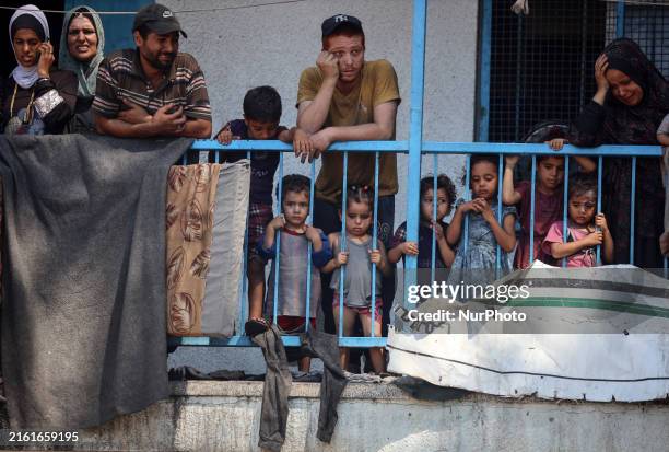 Palestinians are looking at a UN school sheltering displaced people, following an Israeli strike, amid the Israel-Hamas conflict, in Nuseirat in the...