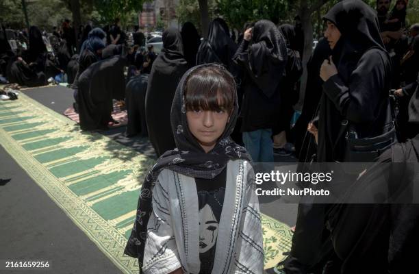 Young girl is posing for a photograph while veiled women are preparing to take part in a mass prayer ceremony during a religious festival to...