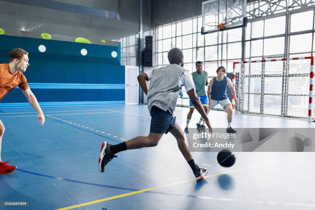 Man playing basketball with his multiracial friends in a sports hall
