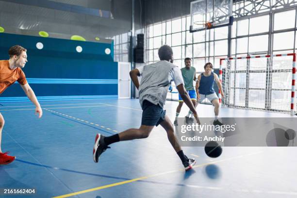 homem jogando basquete com seus amigos multirraciais em um salão esportivo - organizações esportivas - fotografias e filmes do acervo