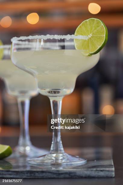 two glasses of margarita cocktail with a lime on the side - mexican culture stock pictures, royalty-free photos & images