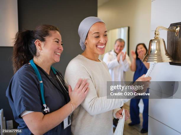 woman chemotherapy patient finishing treatment with a ceremonial bell ring - sympathy card stock pictures, royalty-free photos & images