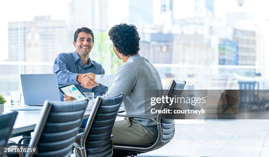 Two businessmen working on a digital tablet and laptop computer in the office in a board room or meeting room. Two businessmen working on a digital tablet and laptop computer in the office in a board room or meeting room.