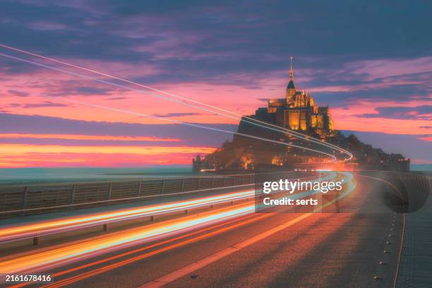 blurred motion long exposure shot traffic at night of mont saint-michel castle illuminated after sunset - castle silhouette stock pictures, royalty-free photos & images