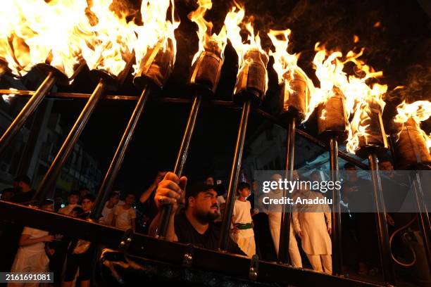 People light torches as they attend a commemoration ceremony for the martyrdom of Prophet Muhammad's grandson Hussein and his 72 companions in...