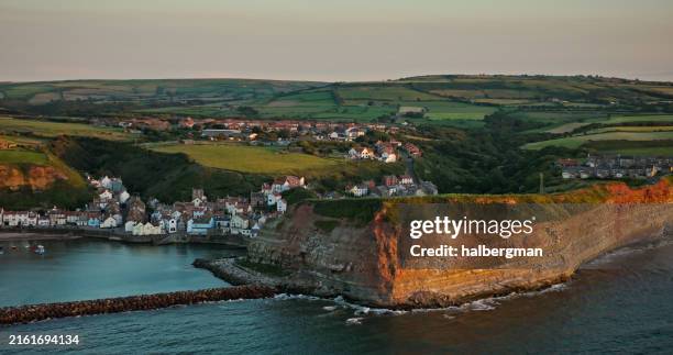 drone shot of the harbour of staithes, north yorkshire at sunset - green grass house stock pictures, royalty-free photos & images
