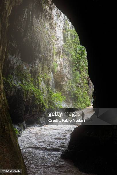 a man standing in a cave with a river flowing below in china - grotte stock-fotos und bilder