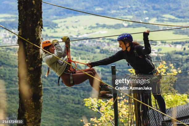caucasian female friends enjoying zipline adventure outdoors - team building stock pictures, royalty-free photos & images