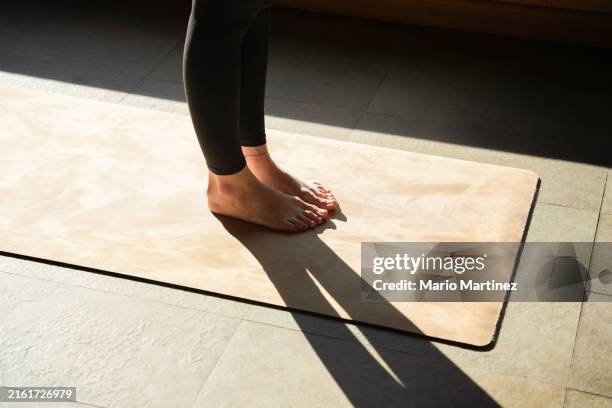 woman practicing yoga standing on mat - tapis de sol photos et images de collection