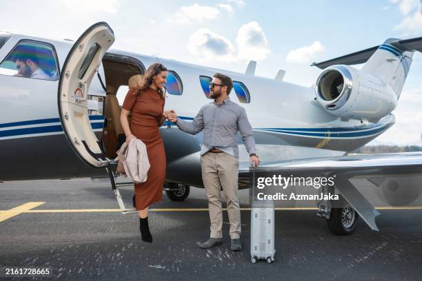 wohlhabendes paar, das nach der reise aus dem privatjet steigt - privatsphäre stock-fotos und bilder