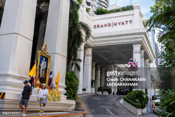 People walk past the main entrance of the Grand Hyatt Erawan hotel in Bangkok on July 17 the day after six bodies were found dead inside the hotel...