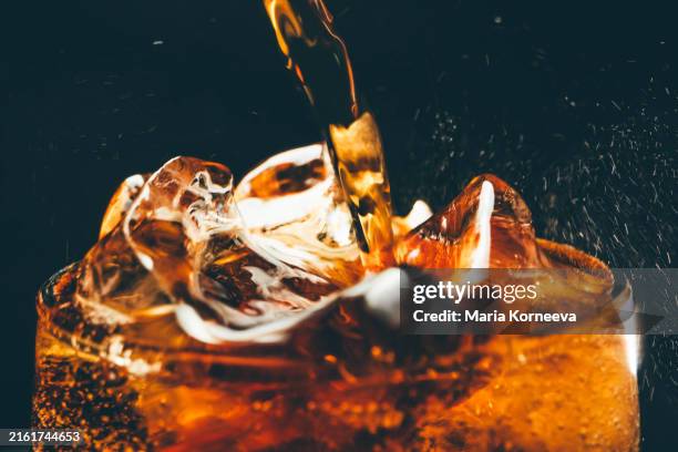 a glass of cold cola with ice cubes. pouring cola close up. - frisdrank stockfoto's en -beelden