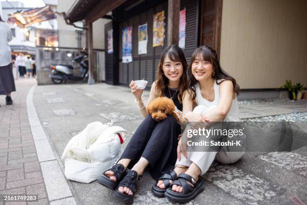 portrait of young female friends sitting on street in traditional japanese festival - toy poodle stock pictures, royalty-free photos & images