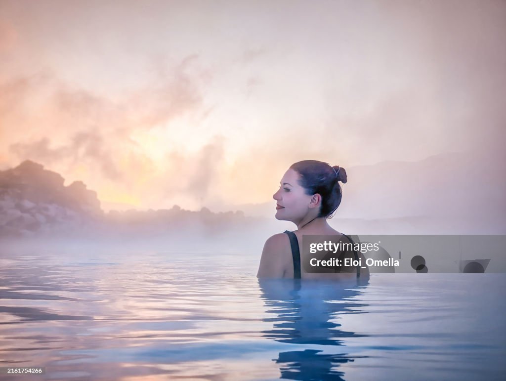 Donna che si rilassa nella sorgente termale nebbiosa in Islanda