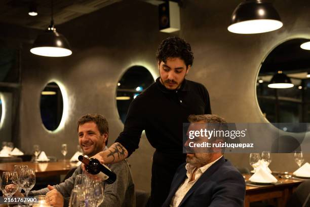 waiter serving wine to male friends diners - guest stock pictures, royalty-free photos & images