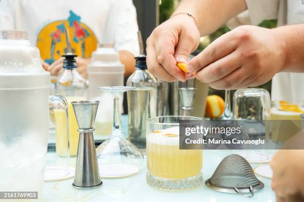 bartender making cocktail, adding some orange peel. - barman learning stock pictures, royalty-free photos & images