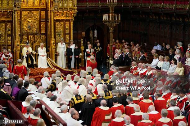 King Charles III, wearing the Imperial State Crown and the Robe of State, looks up as he reads the King's Speech alongside Queen Camilla, wearing the...
