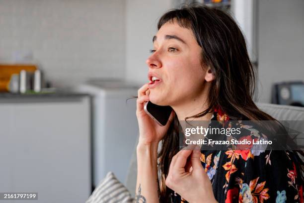 joven enojada hablando por teléfono móvil en casa - quejándose fotografías e imágenes de stock