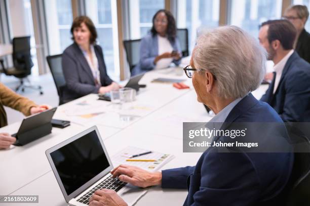 senior businessman listening to colleagues during meeting in office - verwaltungsrat stock-fotos und bilder