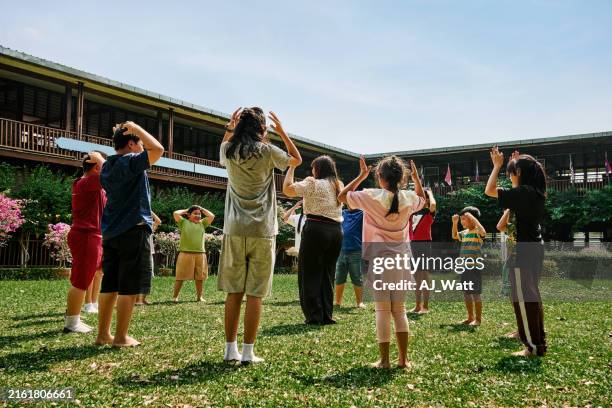 fröhliche kinder, die im kreis mit lehrer auf dem schulhof spielen - sommercamp stock-fotos und bilder