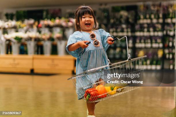 cute asian toddler girl carrying shopping basket, doing grocery shopping in supermarket - basket stock pictures, royalty-free photos & images