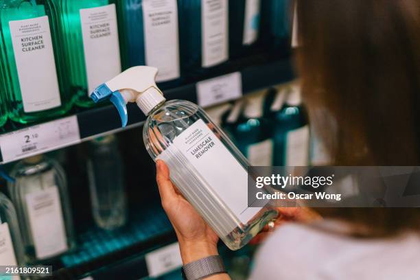 young woman choosing cleaning products for home at supermarket - cleaning agent stock pictures, royalty-free photos & images