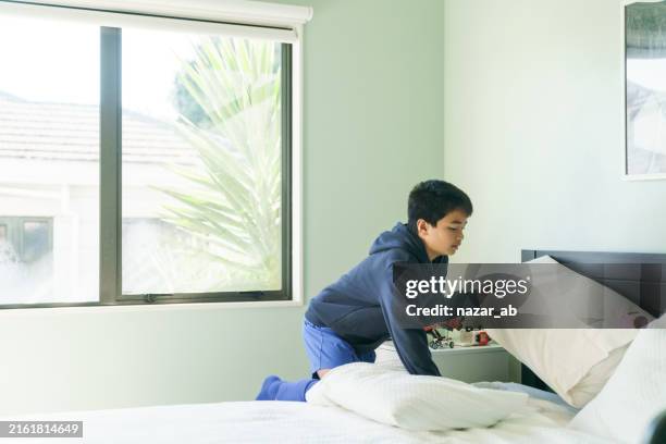 boy changing bed linens in his room. - quarto arrumado imagens e fotografias de stock