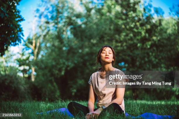 young asian woman practising mindfulness and yoga in nature - zen-like stock pictures, royalty-free photos & images