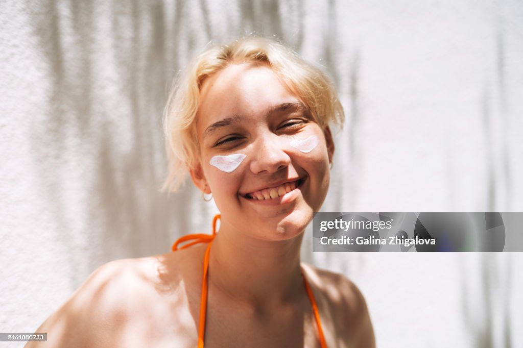 Portrait of smiling teenage girl with sunscreen on her face