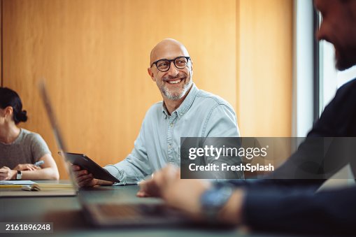 Smiling Businessman in Team Meeting with Colleagues in Office Smiling Businessman in Team Meeting with Colleagues in Office