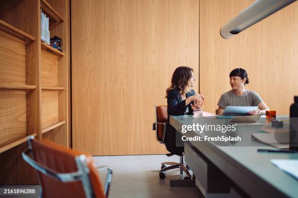 two businesswomen having a meeting in a modern office - beauty class stock pictures, royalty-free photos & images