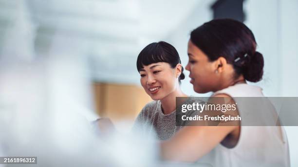 two women collaborating in a modern office environment - participante imagens e fotografias de stock