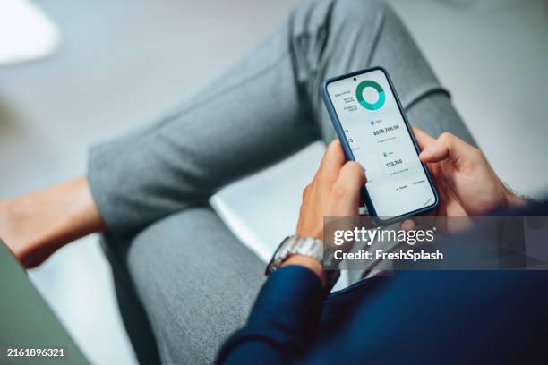 man checking financial data on smartphone at workplace - mobiel stockfoto's en -beelden