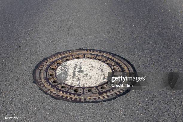 manhole cover on a road - manhole stock pictures, royalty-free photos & images