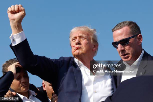 Republican presidential candidate former President Donald Trump pumps his fist as he is rushed offstage during a rally on July 13, 2024 in Butler,...