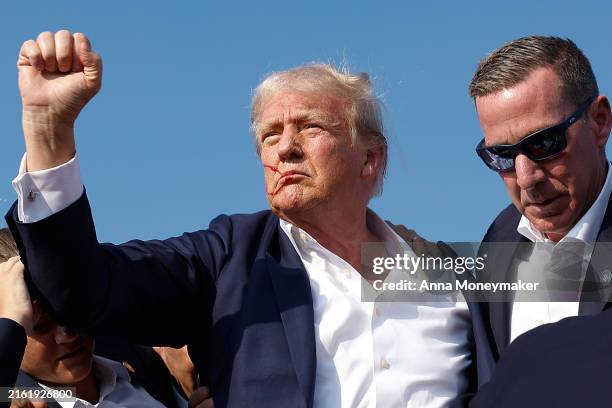 Republican presidential candidate former President Donald Trump pumps his fist as he is rushed offstage by U.S. Secret Service agents after being...