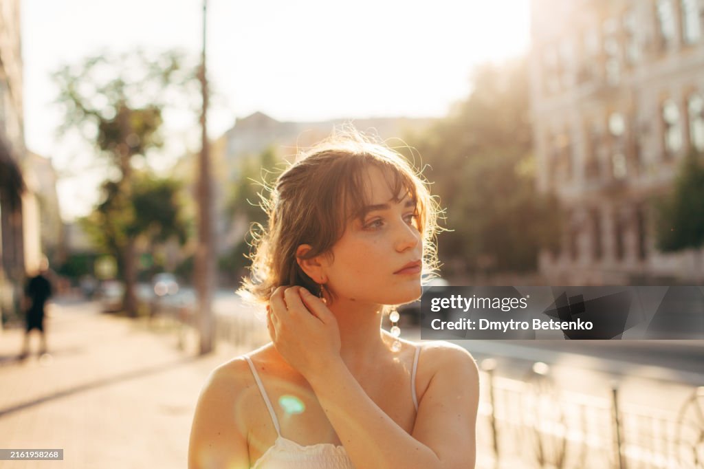 Beautiful young woman walking on the city street during summer
