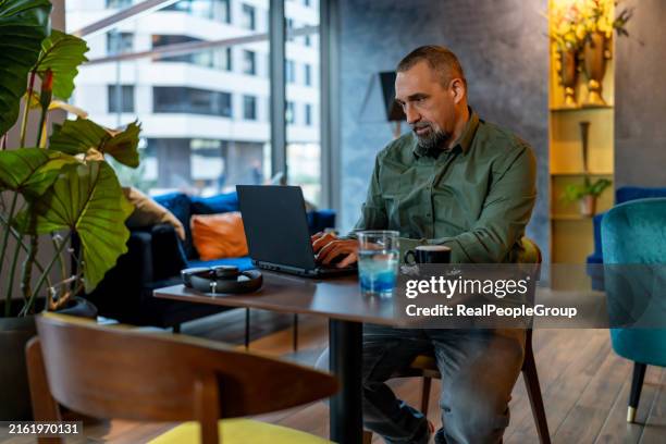 mann, der an laptop arbeitet in einem modernen, gemütlichen loungebereich - komfortzone stock-fotos und bilder