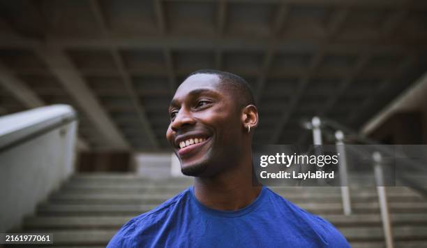 close-up of young man smiling happily, looking sideways outdoors - een dag uit het leven serie stockfoto's en -beelden