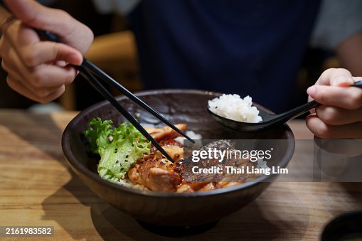 A cropped image of a woman’s enjoying Japanese Donburi, Chicken Teriyaki with rice in a Japanese restaurant A cropped image of a woman’s enjoying Japanese Donburi, Chicken Teriyaki with rice in a Japanese restaurant