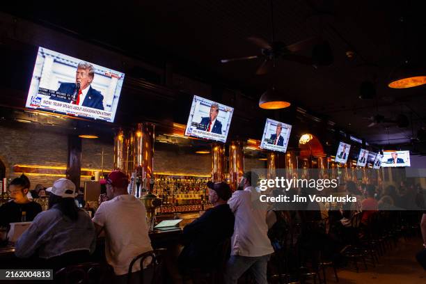 People watch as Donald Trump's GOP candidate acceptance speech is broadcast inside a bar on the final night of the RNC on July 18, 2024 in Milwaukee,...