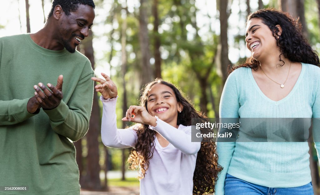 Multiracial girl with mother and friend, dancing in park