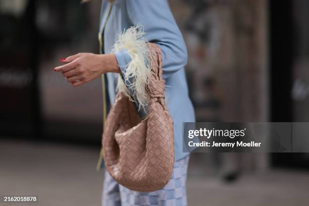 Sonia Lyson is seen wearing a light blue pajama shirt with yellow piping along the seams and yellow ostrich feather cuffs; the beige braided leather...