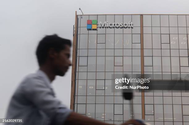 Man is riding his bike past an office building of Microsoft in Gurugram, in the outskirts of New Delhi, India, on July 19, 2024. Airlines,...