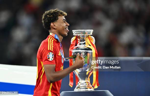 Lamine Yamal of Spain celebrates with his Winners Medal as he walks past the UEFA Euro 2024 Henri Delaunay Trophy following victory in the UEFA EURO...