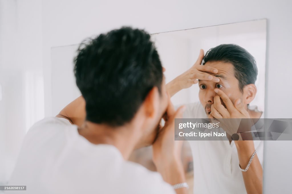 Man putting in contact lenses in bathroom