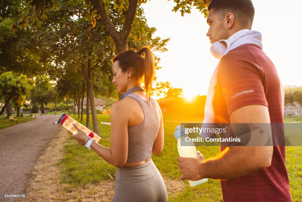 Atletas caucasianos, parando durante sua atividade ao ar livre para se refrescar com suplementos energéticos / de saúde