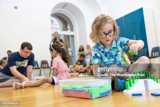 Conway Myers 5, puts dominoes in a formation during a class at the Destination Domino special exhibition at the National Building Museum on July 13,...