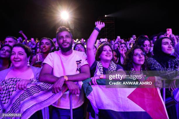 Palestinian flag and a checkered head scarf hang on a barrier as fans cheer during the Egyptian band Cairokee's first concert in Lebanon, at the...